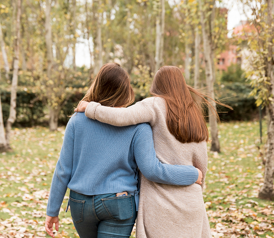 Rebecca Roby - Two women walking outdoors with their arms around each other.